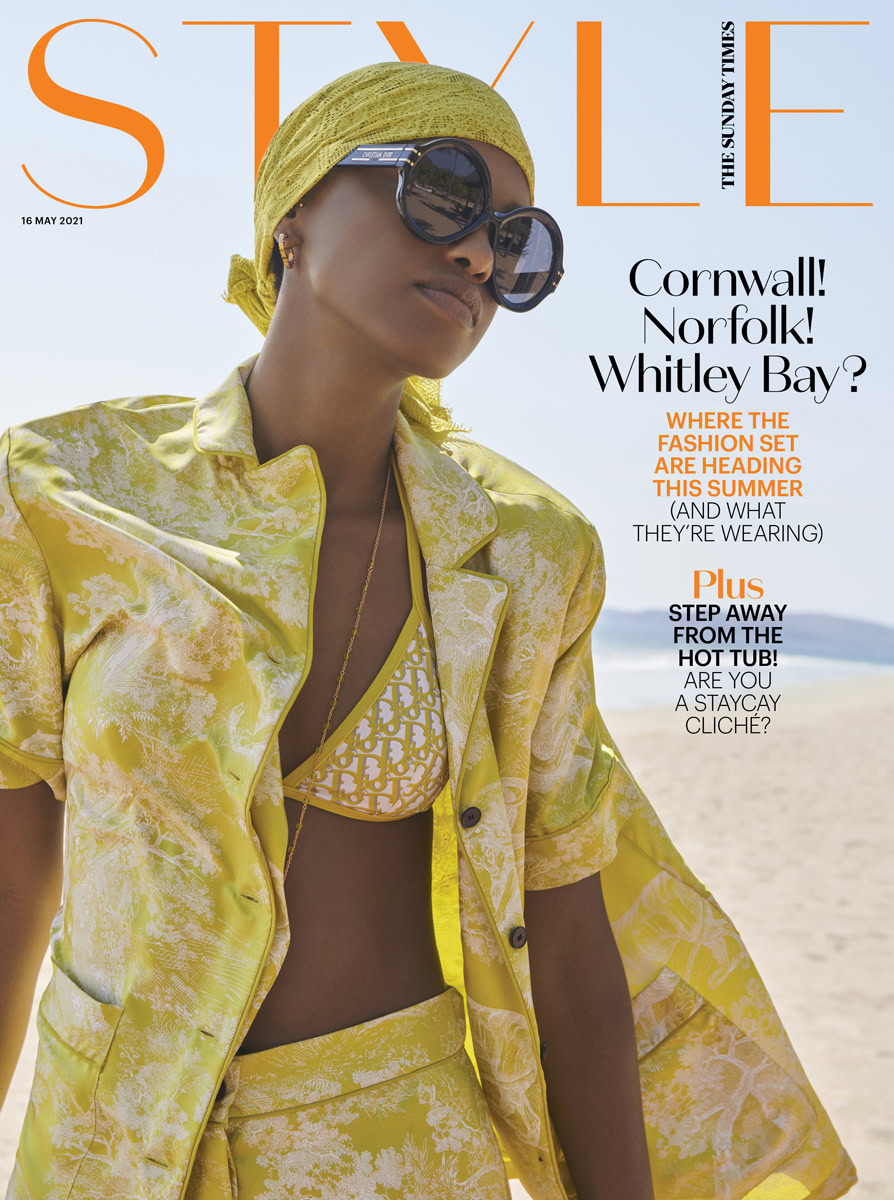 Vibrant fashion editorial portrait of a woman wearing a yellow patterned suit and designer swimwear on a beach, showcasing summer fashion, sunglasses, and accessories by Pamela Hanson Photography.