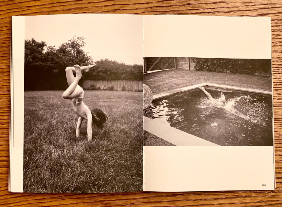 Young girl performing a handstand outdoors on a grassy lawn, black-and-white photography, artistic and candid shot capturing movement and grace.