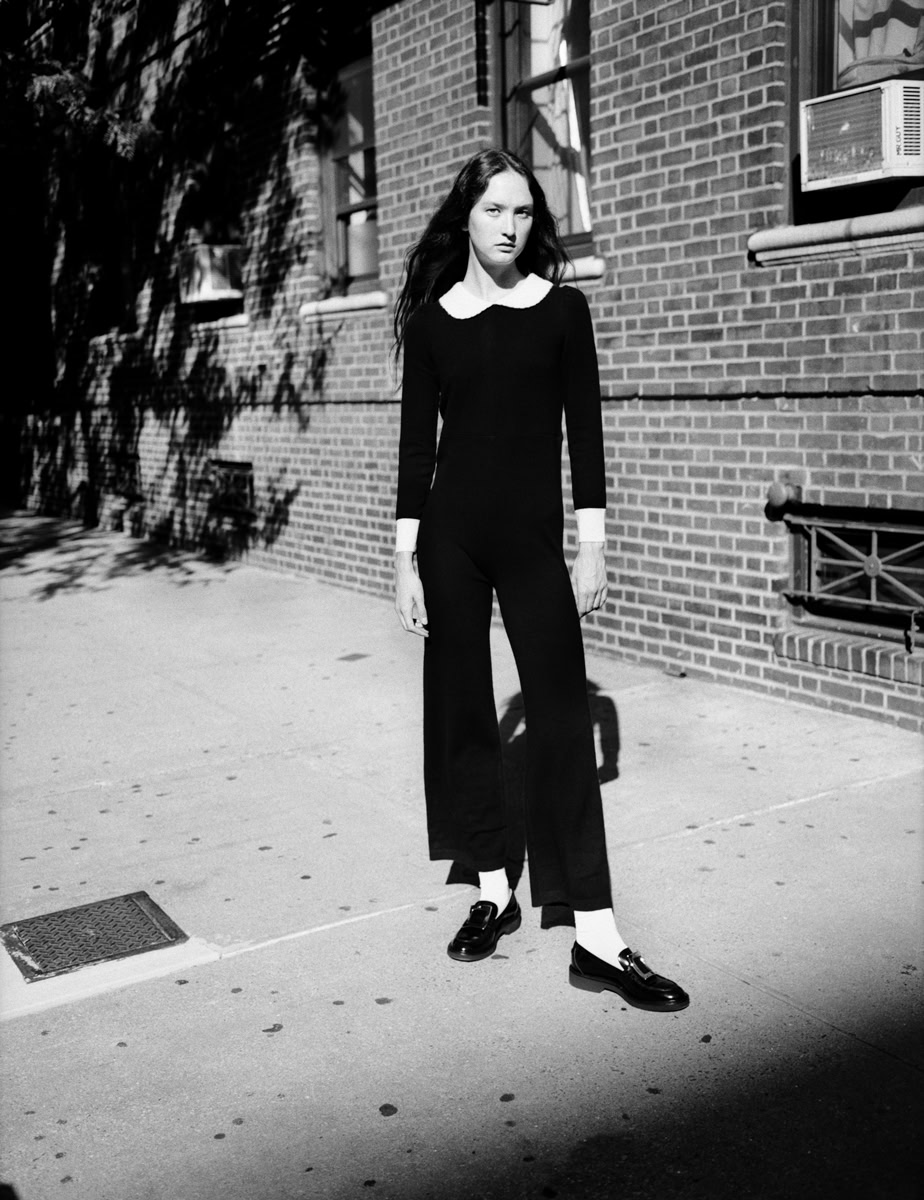 Elegant black and white fashion photograph of a woman standing on a city sidewalk, showcasing Pamela Hanson Photography's high-end editorial portrait style.