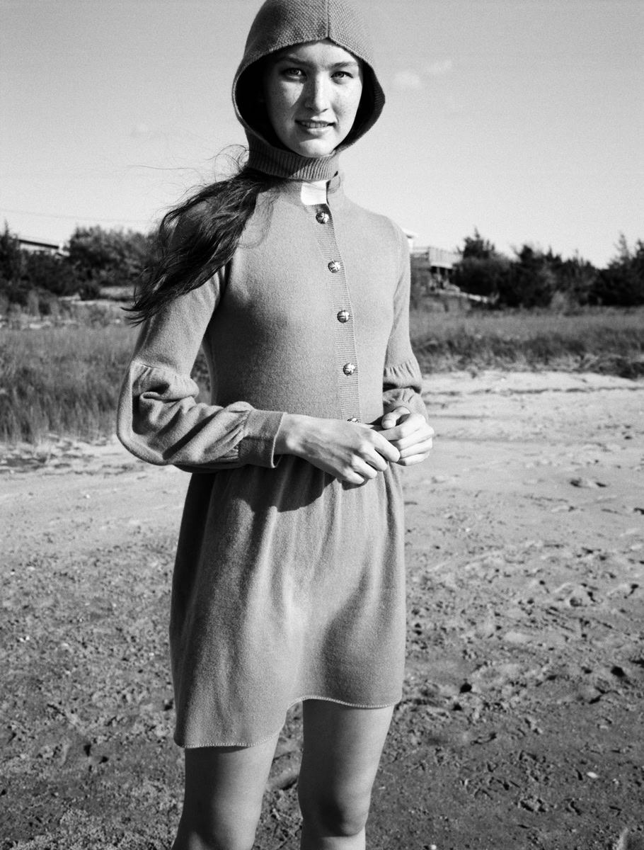 Elegant black and white portrait of a young woman in vintage-style clothing on a sandy beach, showcasing fine art photography with a timeless aesthetic.