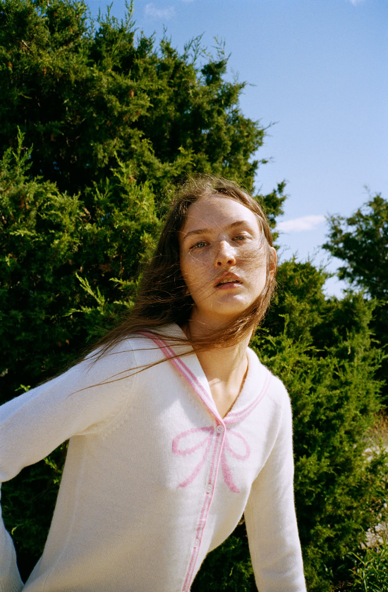 Elegant portrait of a young woman outdoors with lush greenery and blue sky, captured by Pamela Hanson Photography for fashion and portrait photography portfolios.