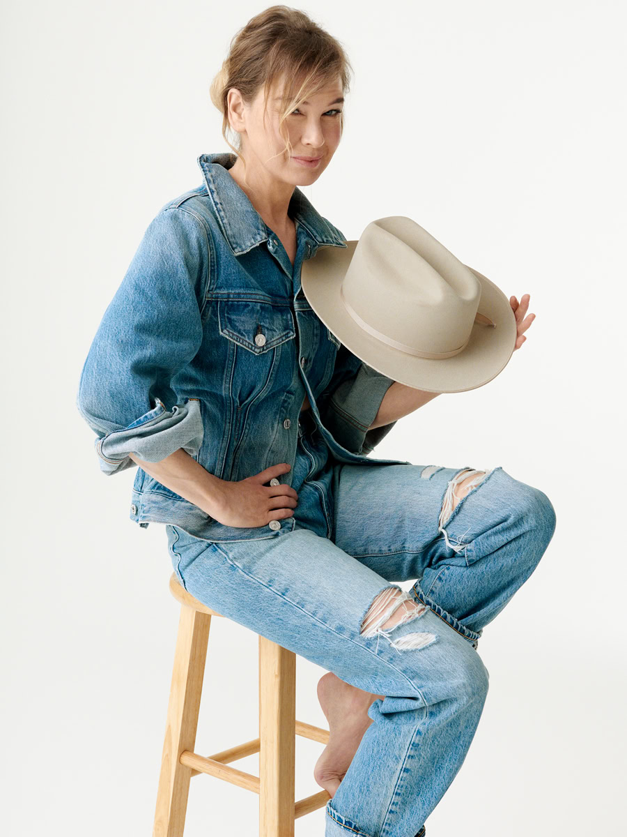 Casual woman portrait in denim jacket and ripped jeans holding cowboy hat, sitting on wooden stool, minimalist studio shoot, fashion and lifestyle photography, Pamela Hanson Photography.