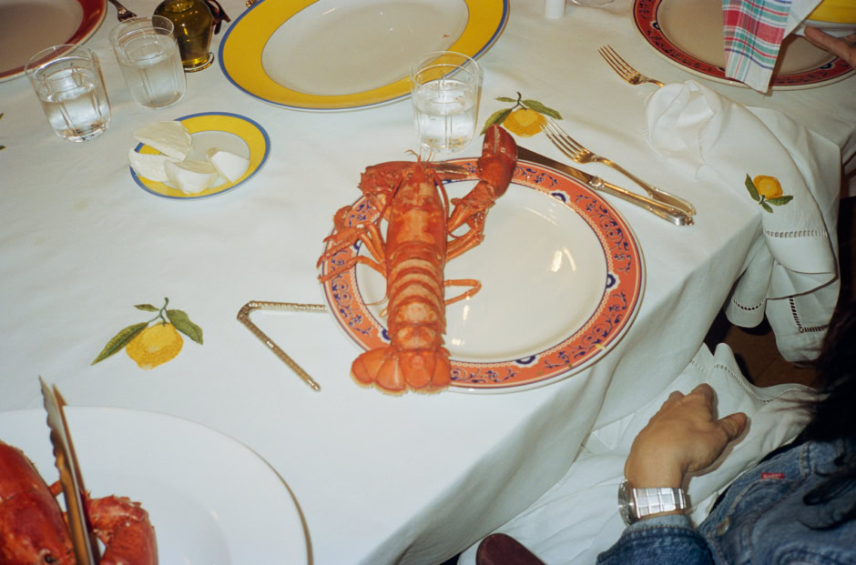 Lobster served on a decorative plate at an elegant dining table with colorful plates and glassware, captured by Pamela Hanson Photography, showcasing fine dining and luxury cuisine photography.
