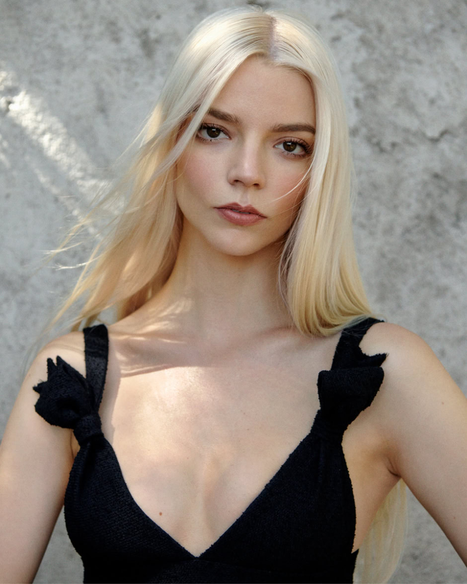 Elegant blonde woman portrait in black dress with strap tie details, natural lighting and textured gray background, showcasing portrait photography by Pamela Hanson.