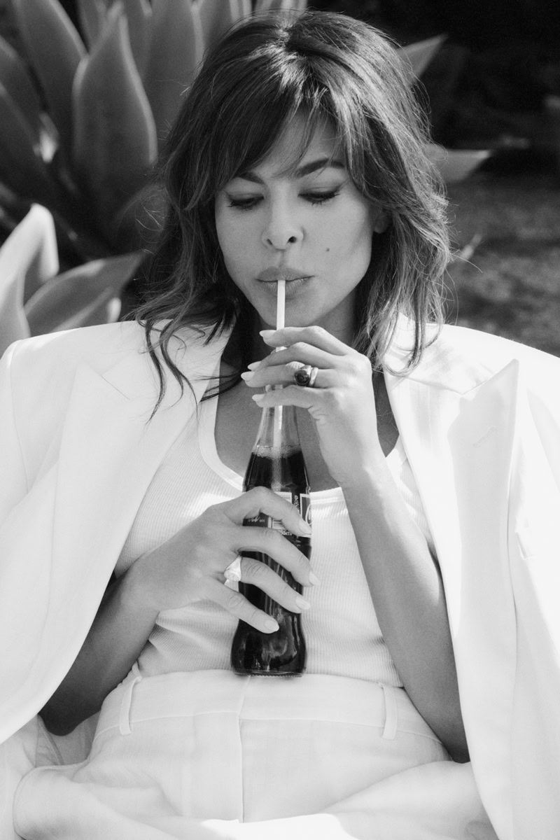 Elegant black and white portrait of a woman sipping a cola soda through a straw, emphasizing sophisticated fashion photography and timeless style.