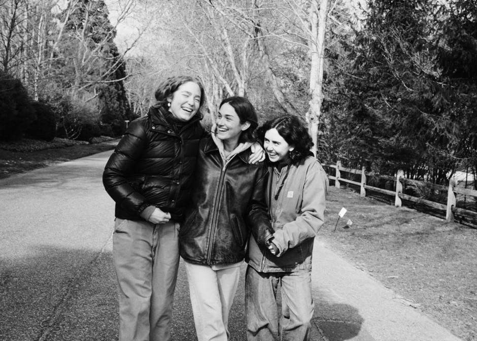 Joyful women outdoors laughing together on a park path, candid moment captured by Pamela Hanson Photography.
