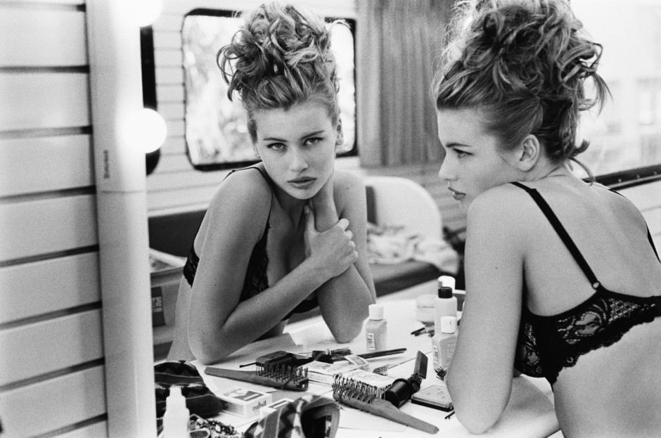 Editorial black and white portrait of a glamorous woman with curly hair in lingerie preparing for photoshoot, makeup, beauty, fashion photography, Pamela Hanson Photography, black and white studio shot.