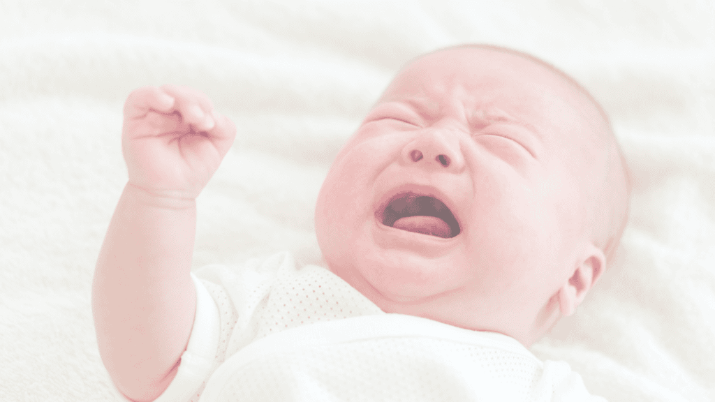 A newborn crying with one fist raised
