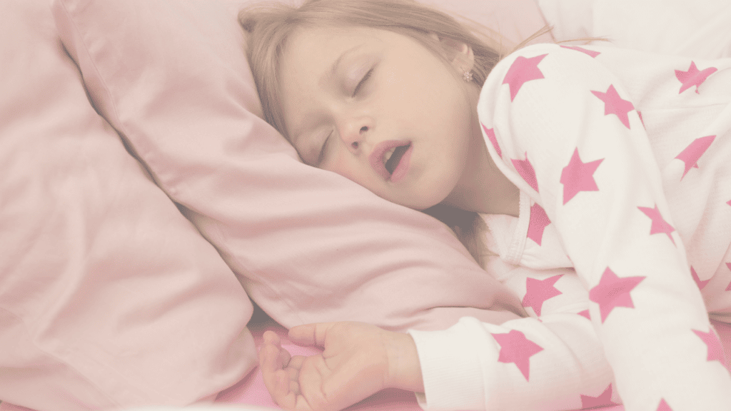 A young girl asleep on a pink pillow with her mouth open