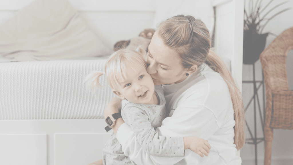 A mother kissing her smiling toddler daughter