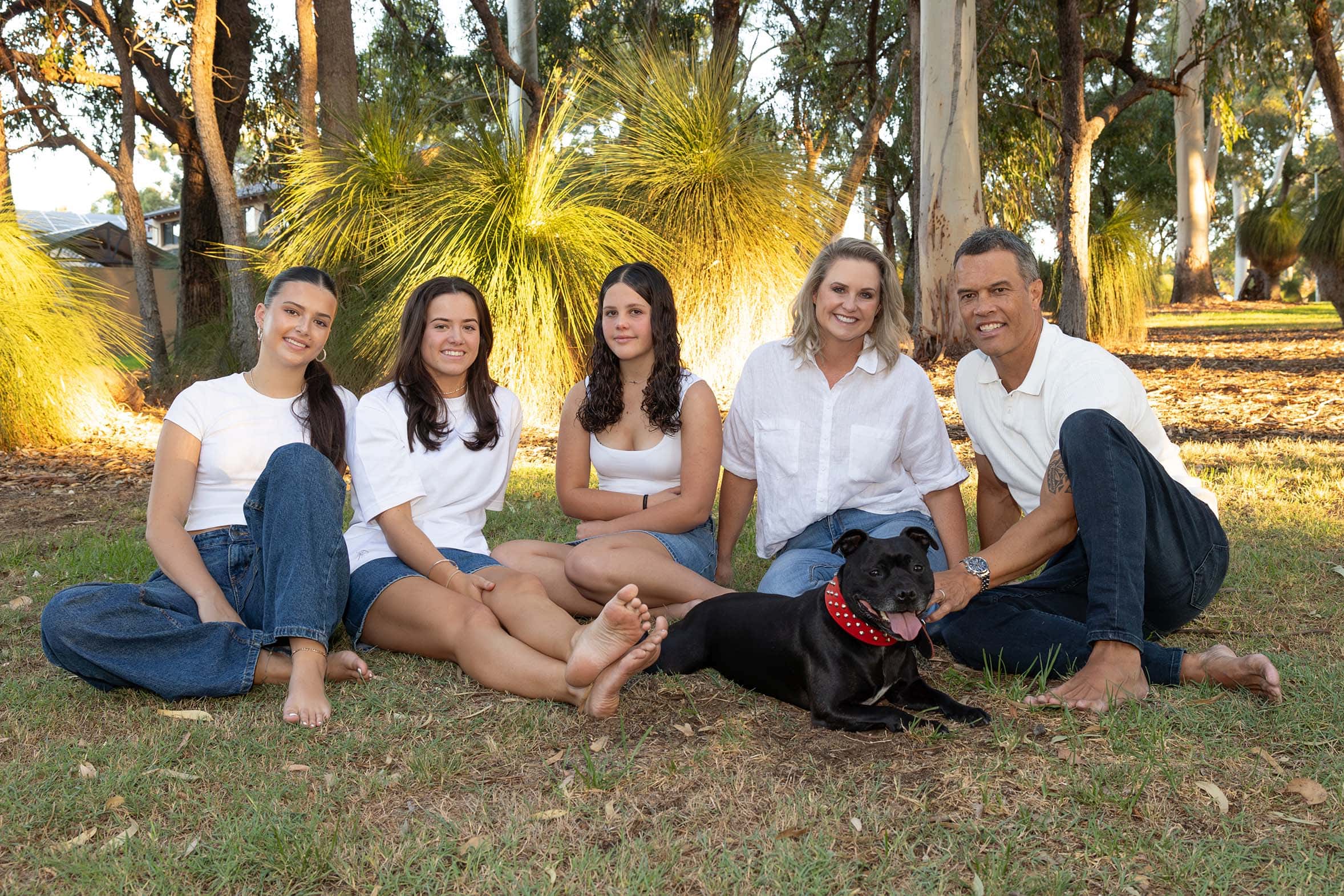 Donna Moala with her husband, three daughters and the family dog sitting on the grass in Australian bushland