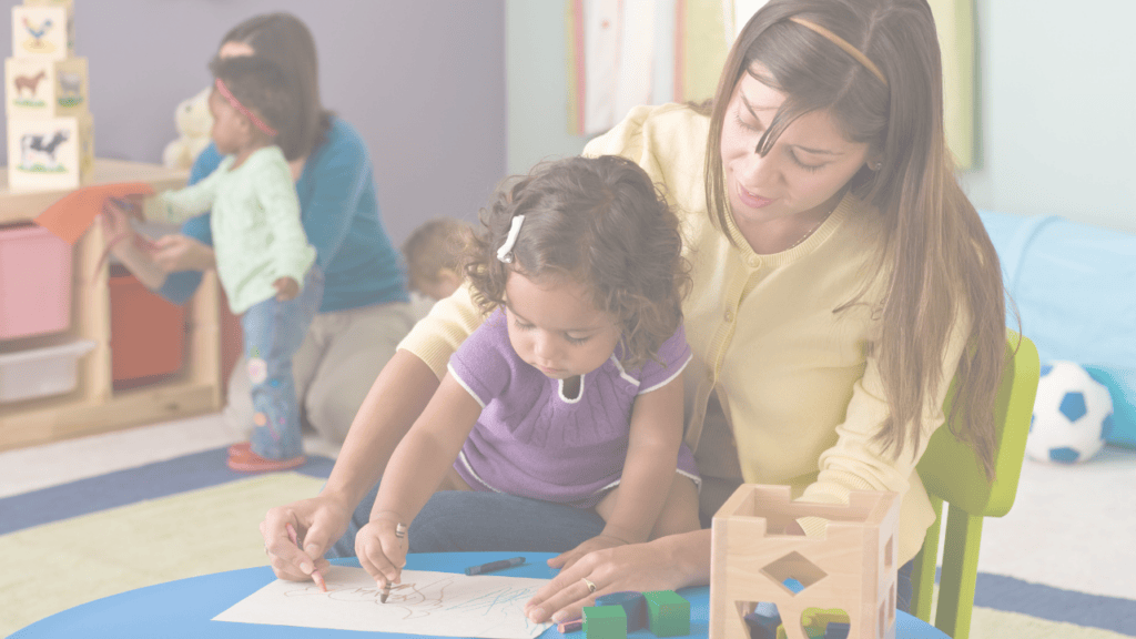 An early childhood educator drawing with a toddler at daycare