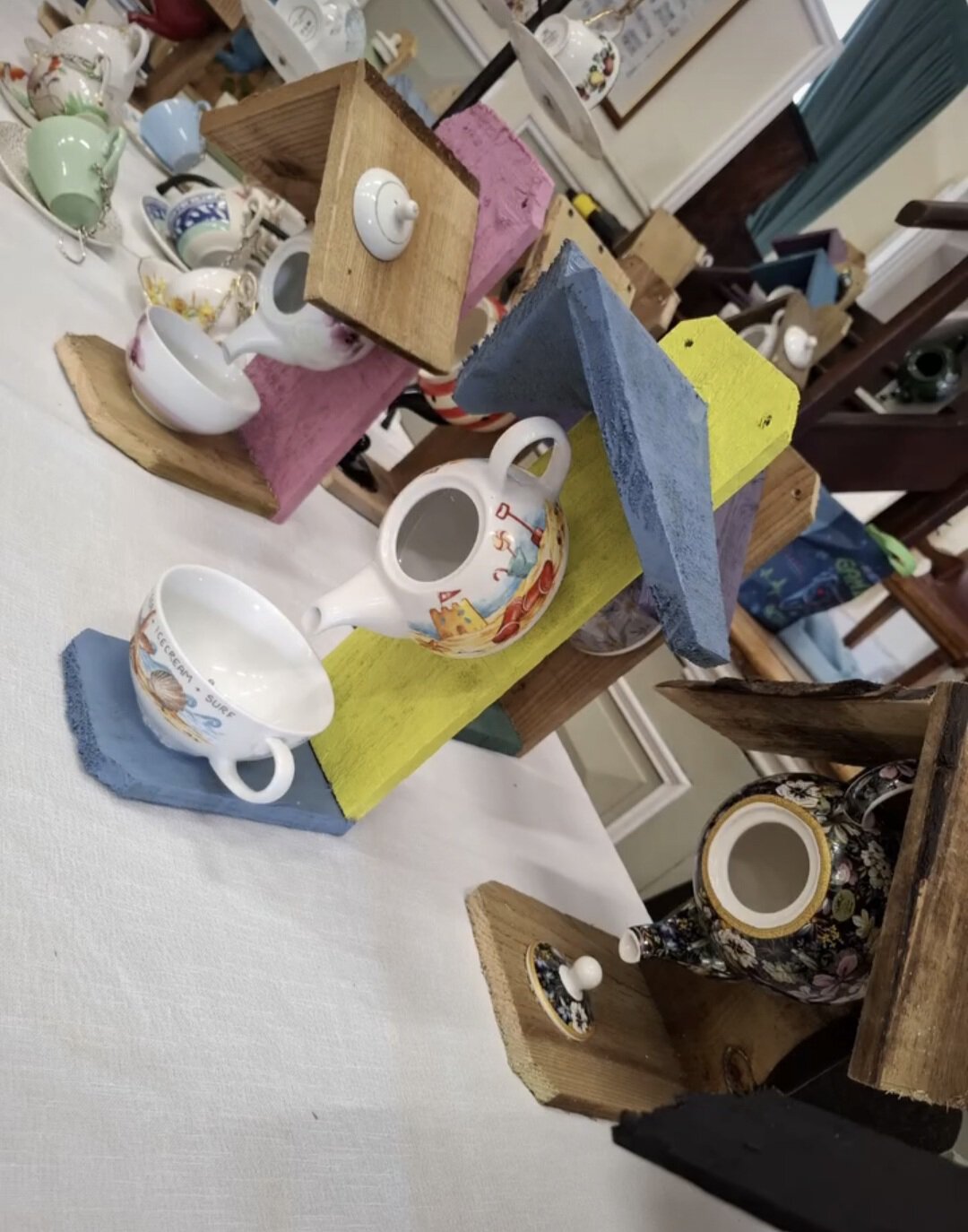 Upcycled wooden bird feeders with colourful painted blocks and ceramic cups, perfect for attracting.