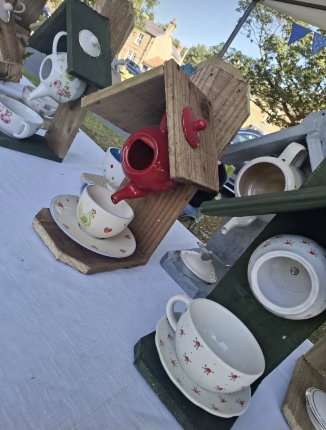 Upcycled wooden bird feeder with teapot and cup details.
