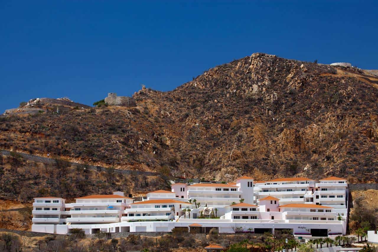 Modern Pedregal Residential Complex Built Into The Hillside With White Structures And Terracotta Roofs Under A Clear Blue Sky.