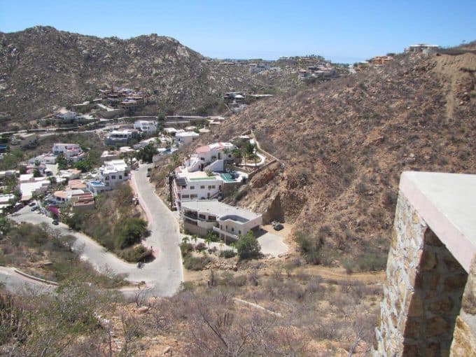Stylish Modern Homes Built Into A Rugged Hillside Landscape In Pedregal, Showcasing Luxury Real Estate And Breathtaking Views Of The Surrounding Desert Terrain And Distant Ocean.
