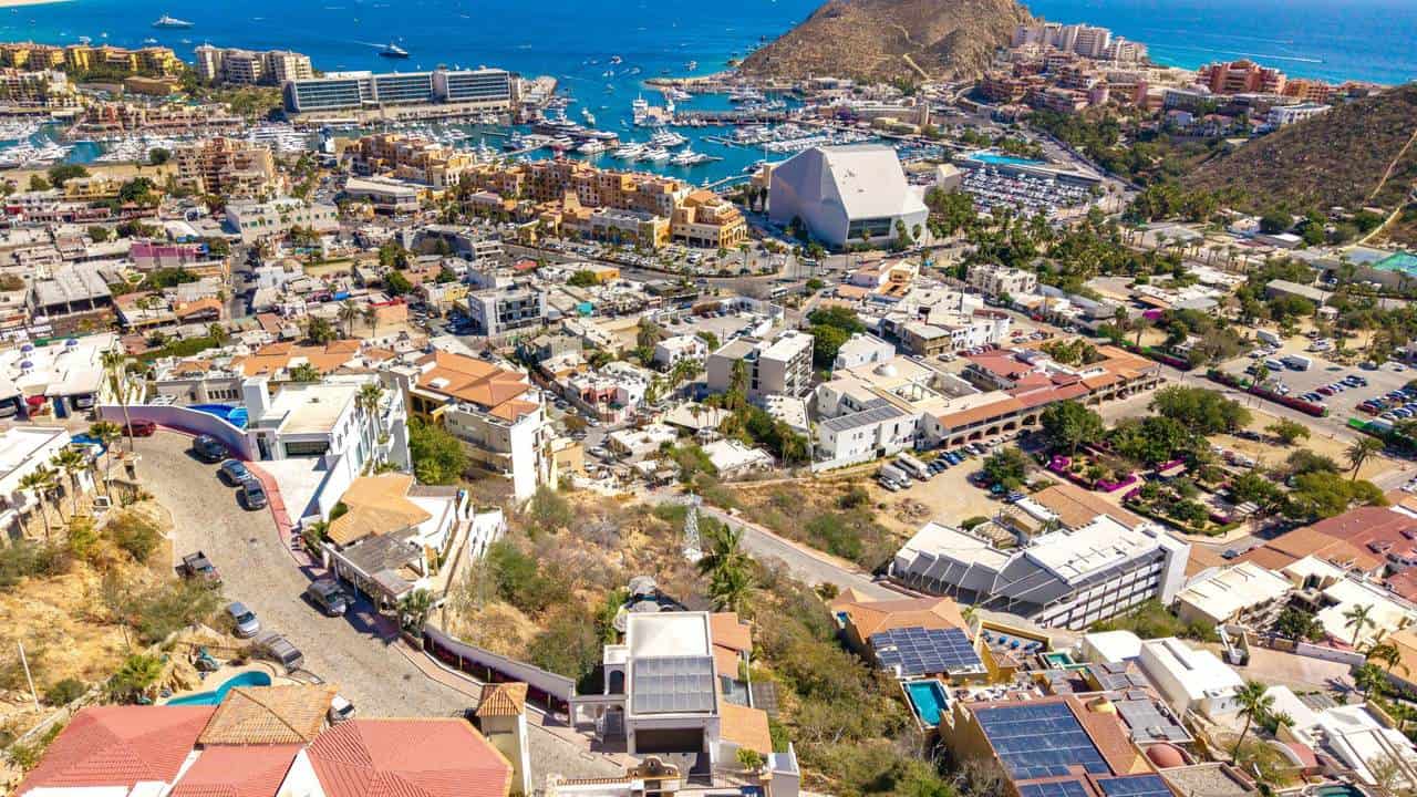 Balcony View Of Pedregal Neighborhood With Water And Marina In The Background, Vibrant Cityscape With Colorful Buildings And Hills, Showcasing Luxury Real Estate In Pedregal, Cabo San Lucas.