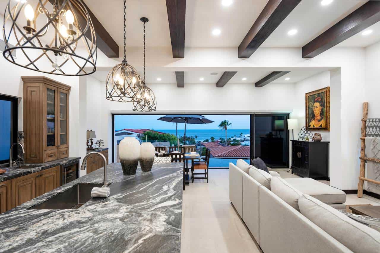 Contemporary Pedregal Living Room With Ocean Views, Featuring A Spacious Open-Concept Design, Elegant Lighting Fixtures, Modern Furniture, And Large Windows That Showcase The Scenic Coastal Landscape.