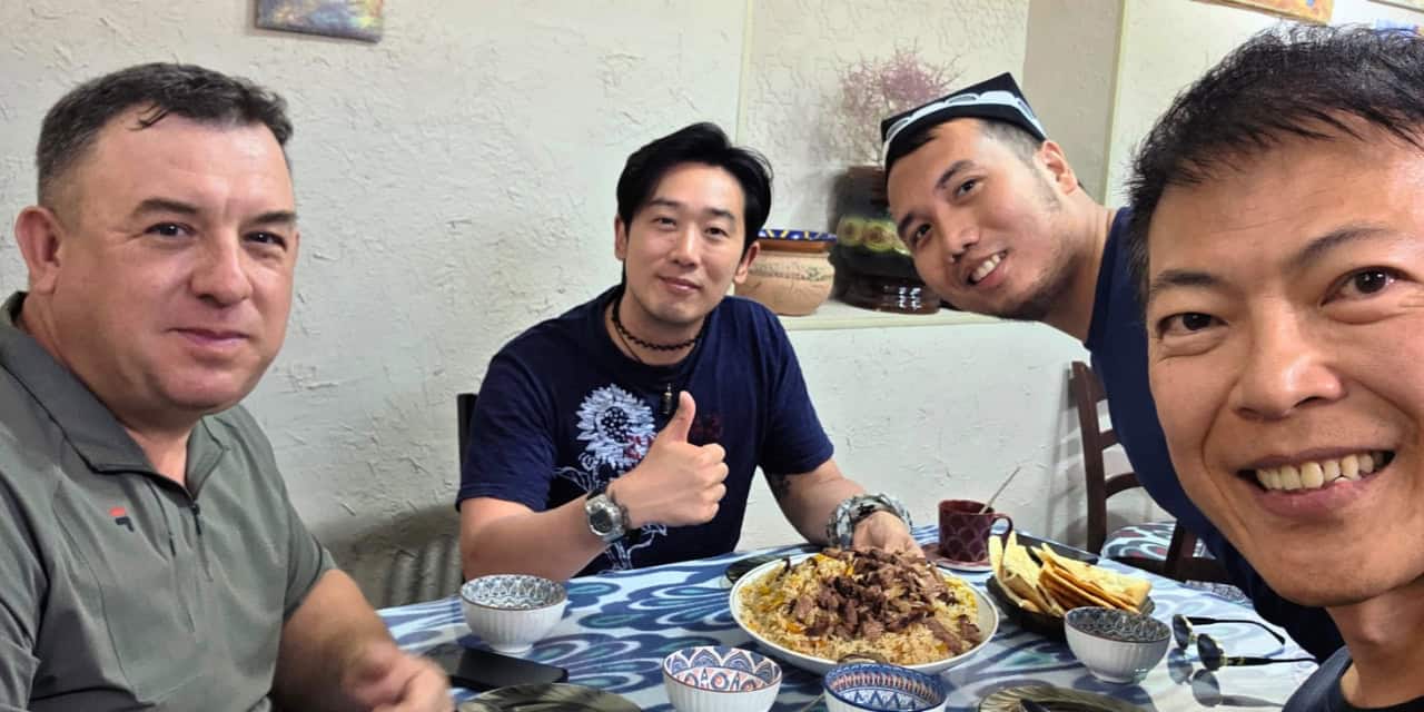 Travelers and their host sharing a traditional Uzbek meal of plov.