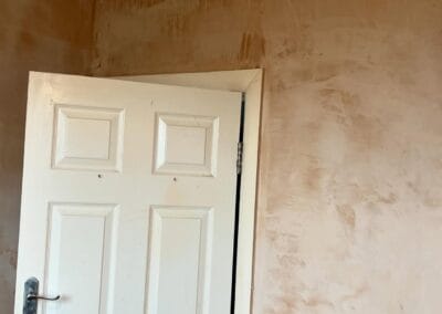 White door in room with unfinished plaster walls.