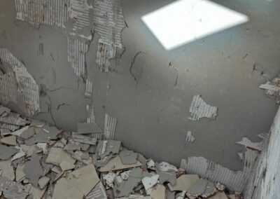 Room with broken plaster and debris on floor.
