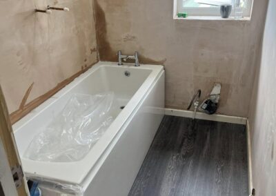 Partially renovated bathroom with bathtub and window.