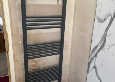 Black towel radiator in bathroom corner.