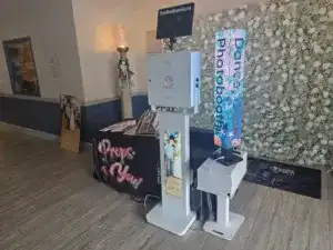Photo booth with floral backdrop and modern equipment at event venue.