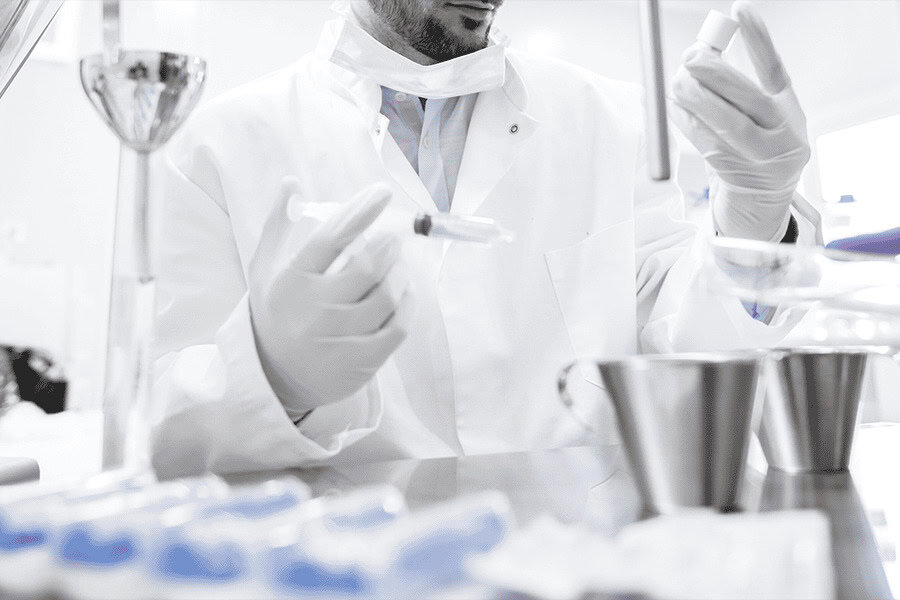 Laboratory worker preparing samples with a syringe and containers during a controlled testing procedure.