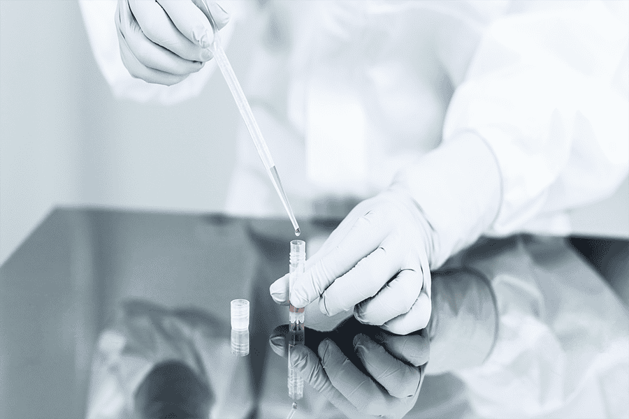 Laboratory worker transferring a liquid sample into a small vial during a controlled testing procedure.