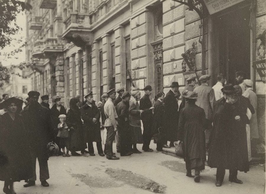 Черга людей біля магазину в старовинному місті, історична фотографія.
