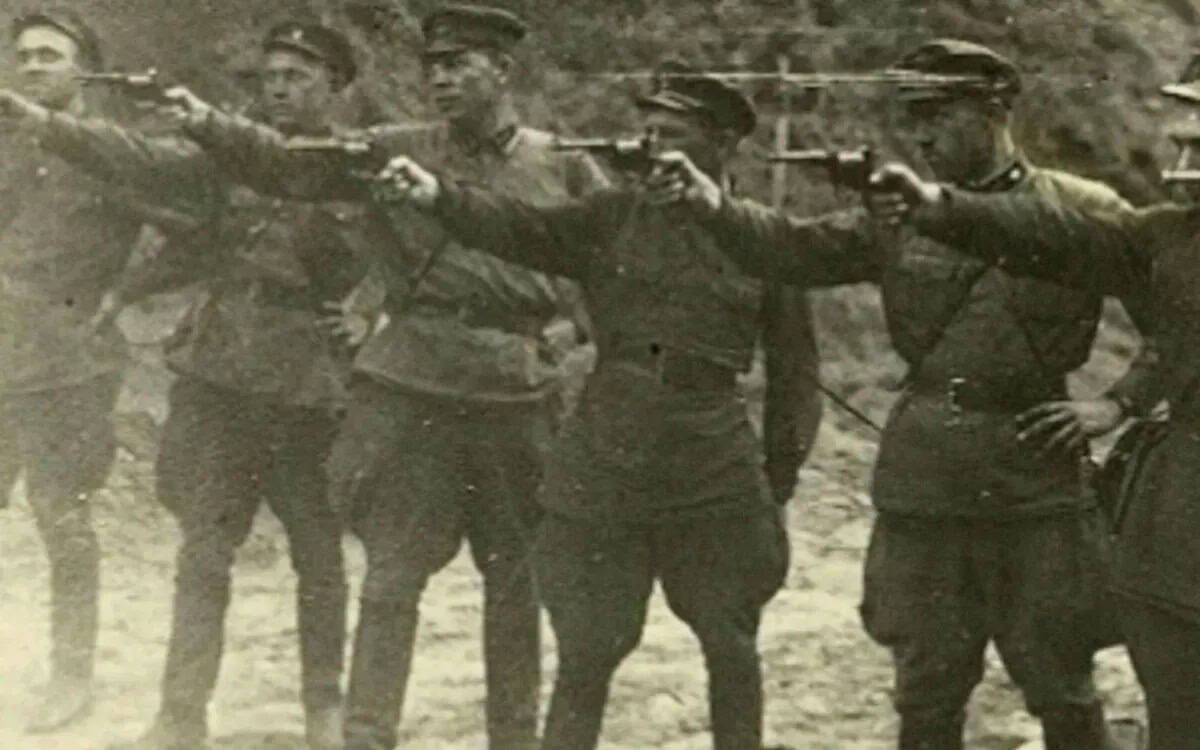Група військових з пістолетами, що стоять у ряд у військовій формі.