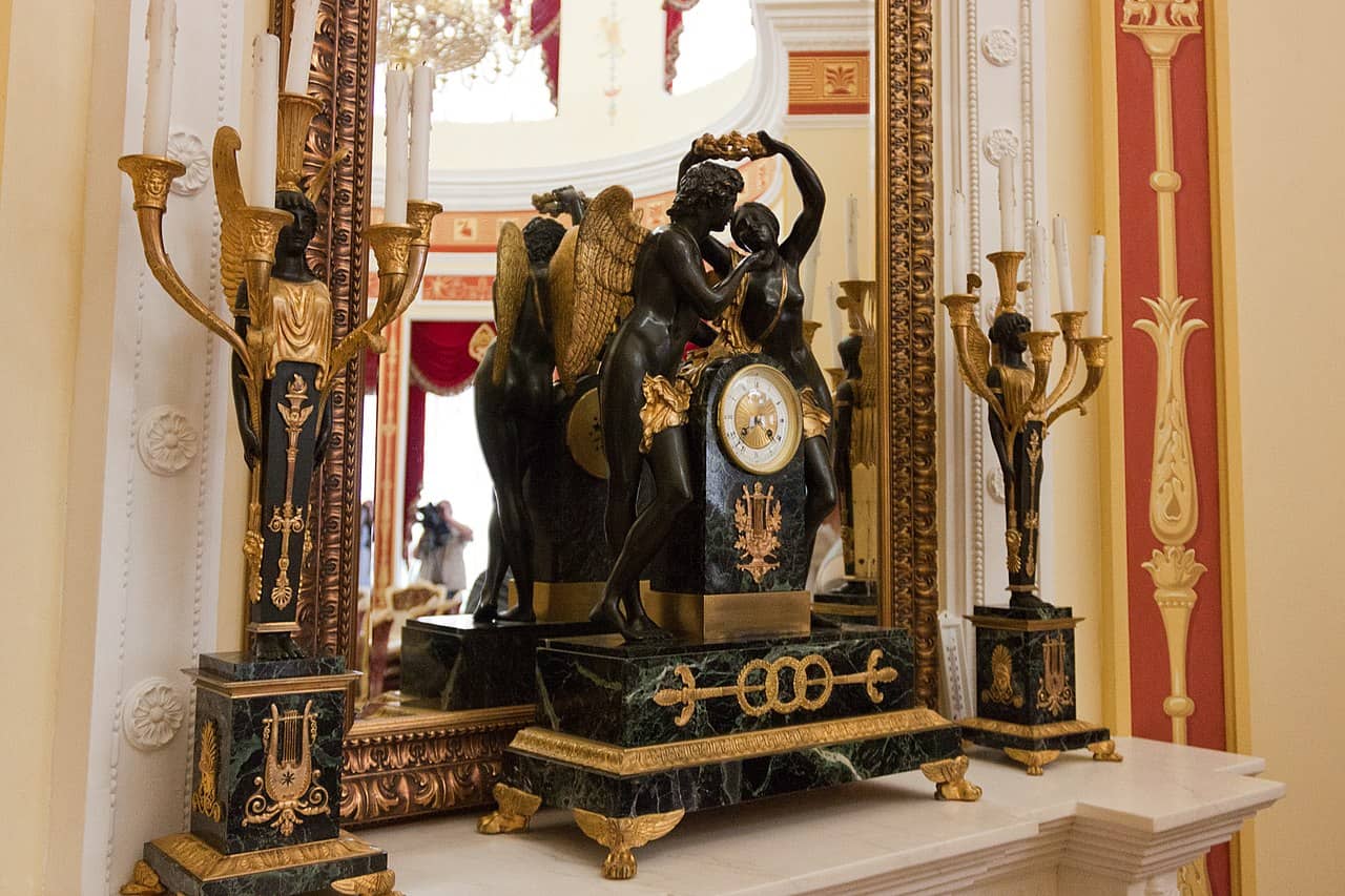 Класичний антикварний настінний годинник з бронзовими фігурами та декоративними елементами.