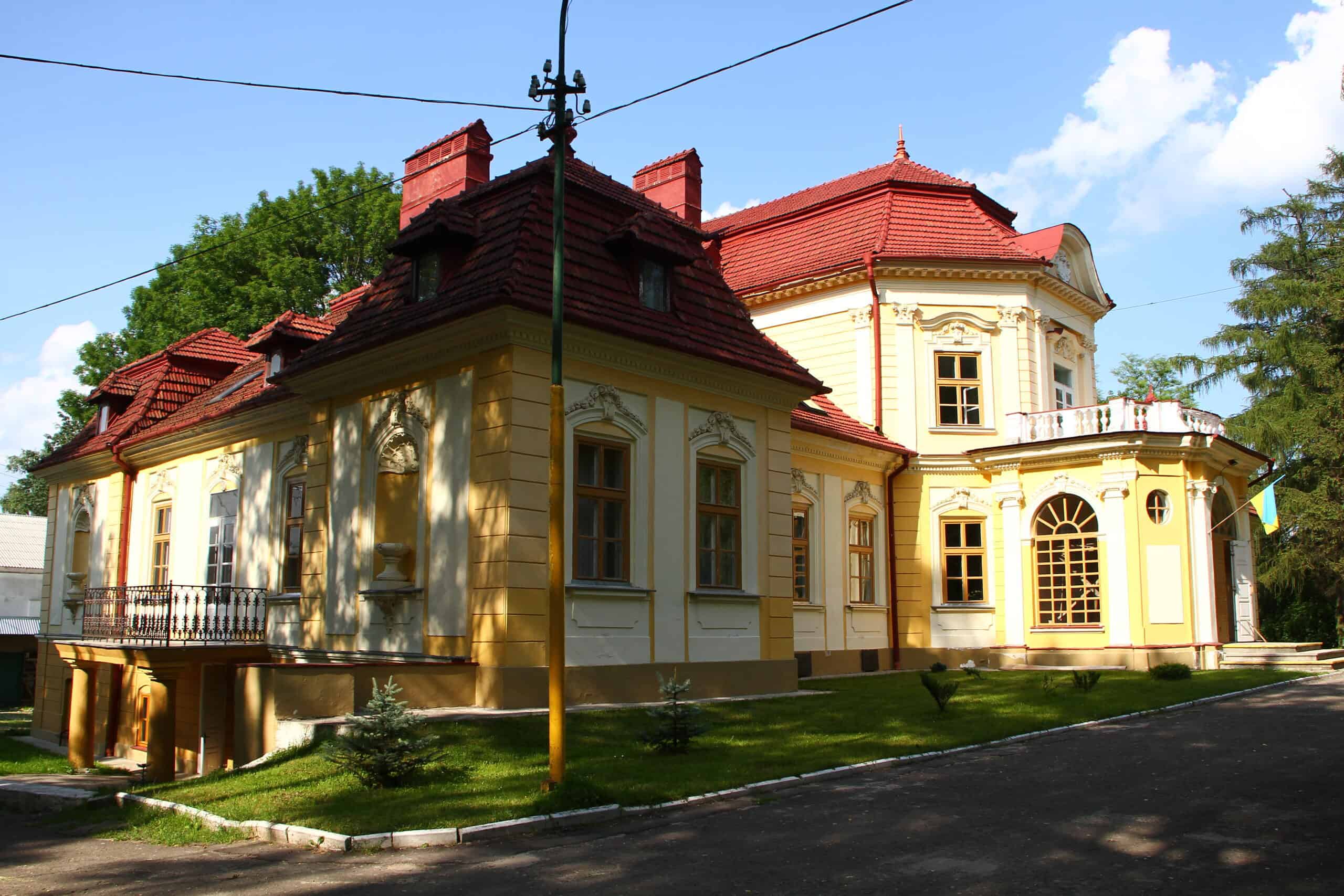 Історична будівля з яскравим фасадом та мальовничим садом у Києві.