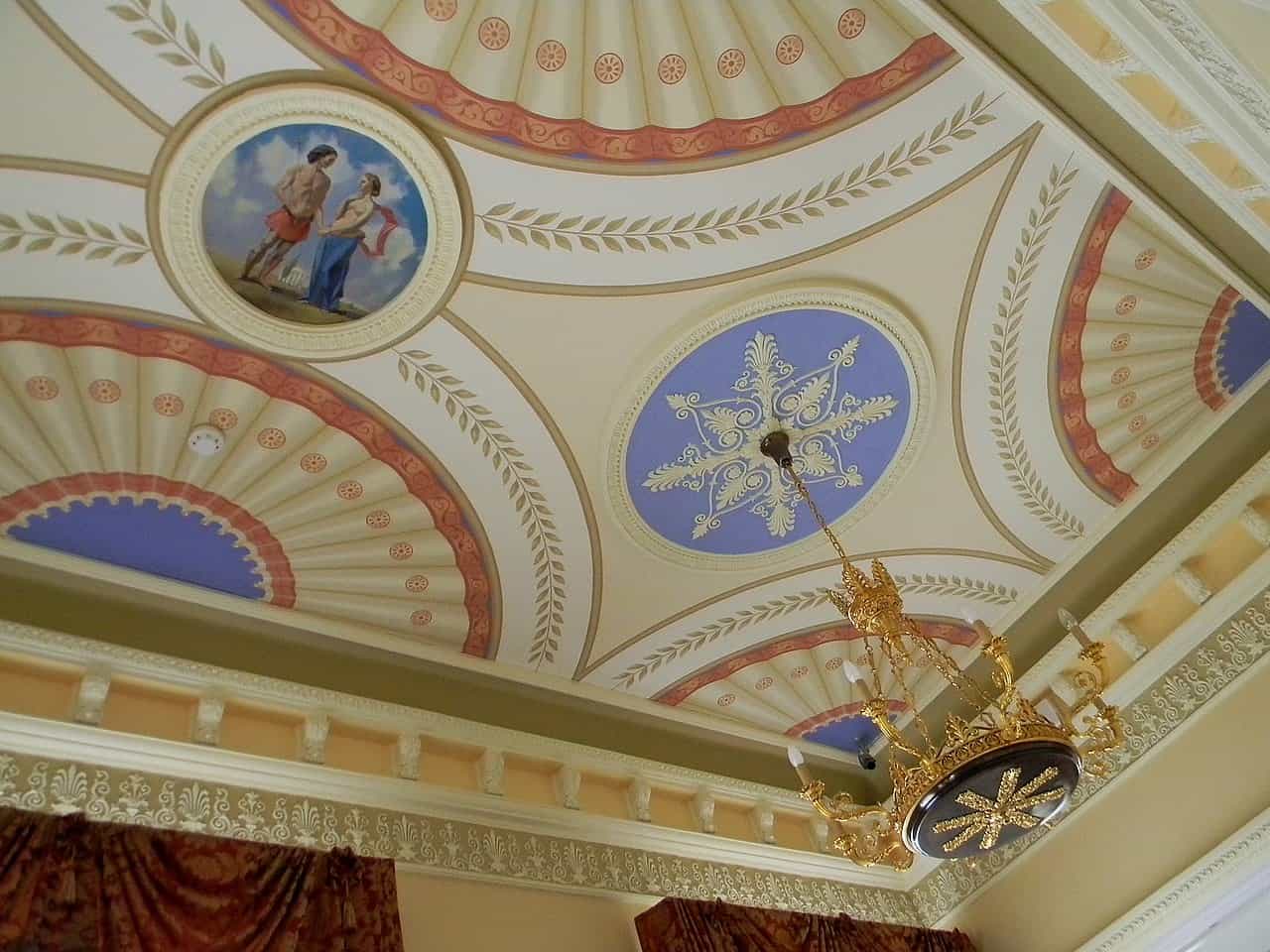 Розкішний інтер'єр з розписами на стелі та люстрою у класичному стилі.
