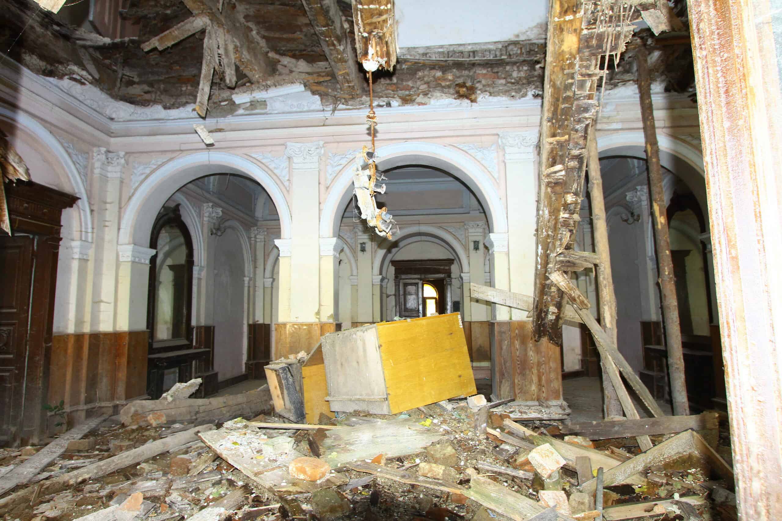 Зруйнована історична будівля з пошкодженими стінами та стелею.