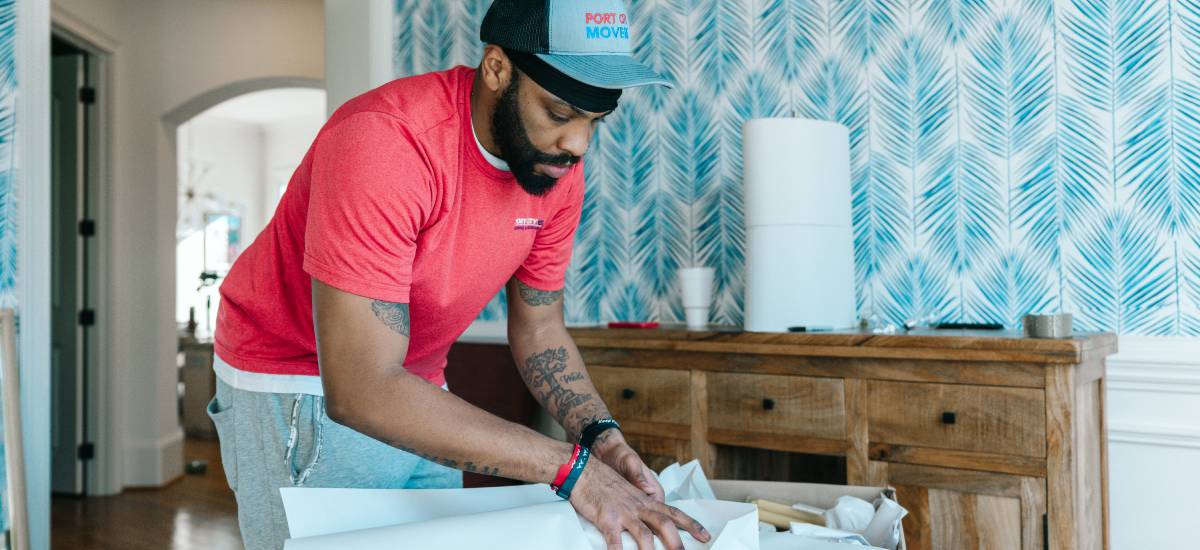 Mover from Port City Movers carefully packing items in home with wrapping paper