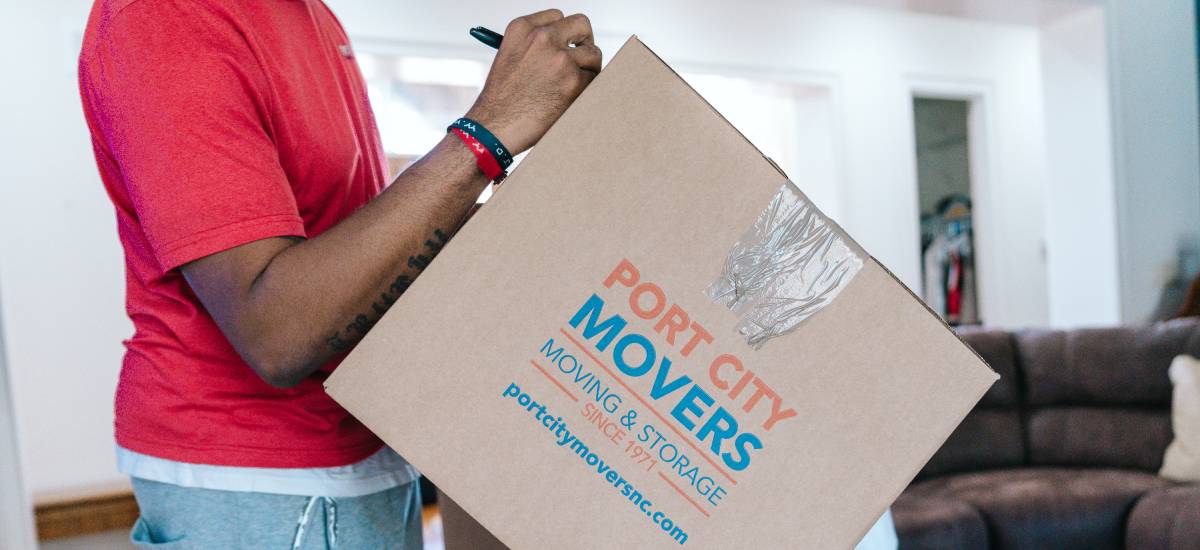 Port City Movers employee labeling a moving box for organized and secure transport.