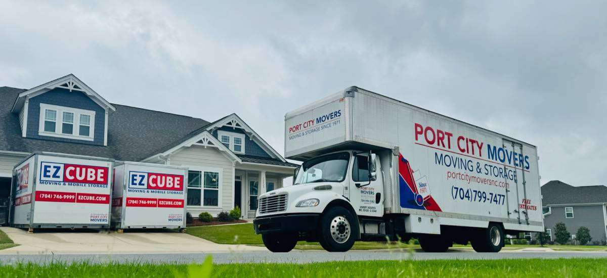 Port City Movers truck and two EZCube mobile storage containers parked in front of a suburban home on a cloudy day.