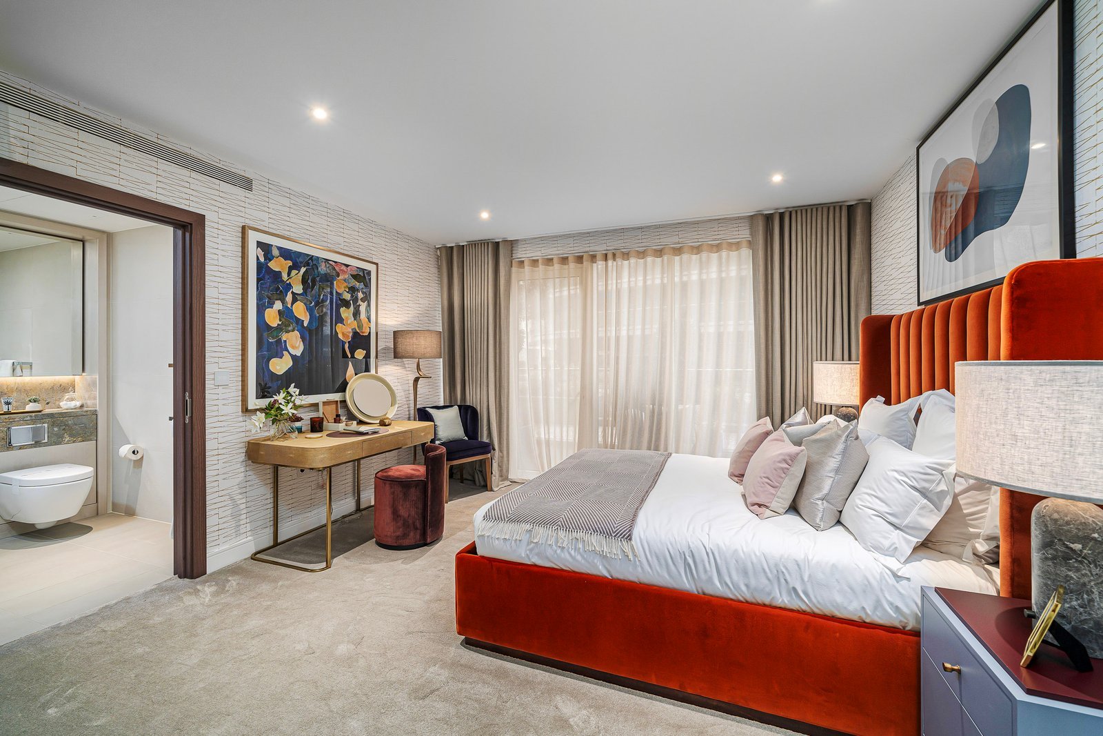 A stylish modern bedroom with orange velvet bed and contemporary decor.