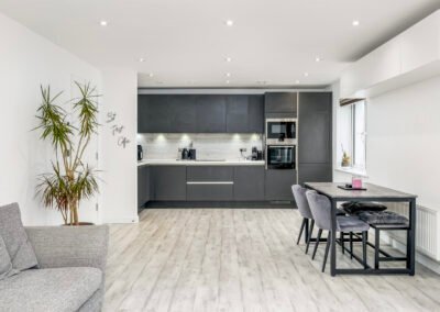 Modern grey kitchen with dining area and large window in contemporary home.