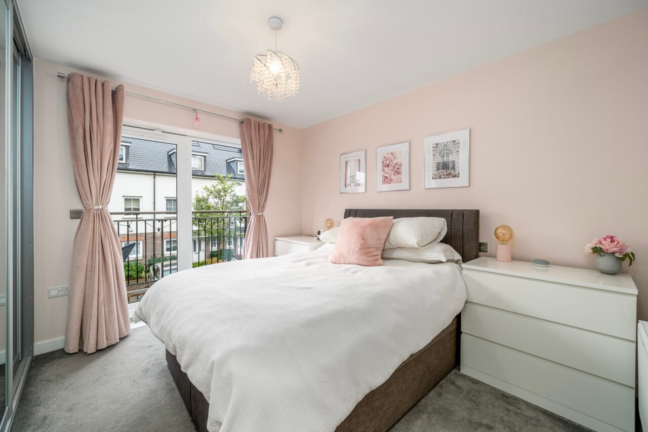 A comfortable bedroom with pink curtains, white bedding, and a balcony view.