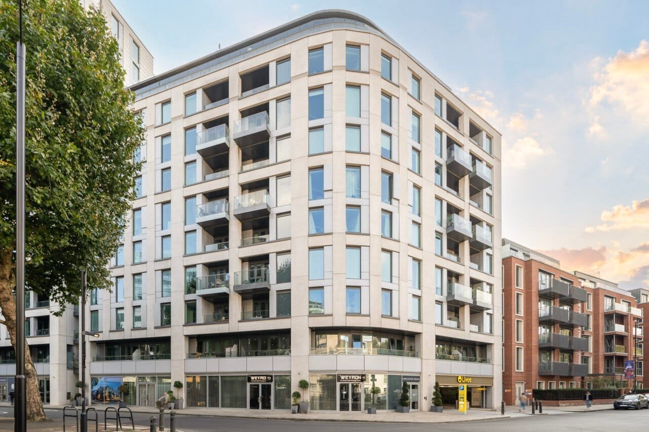 Modern multi-storey residential building with large windows and balconies in an urban setting.