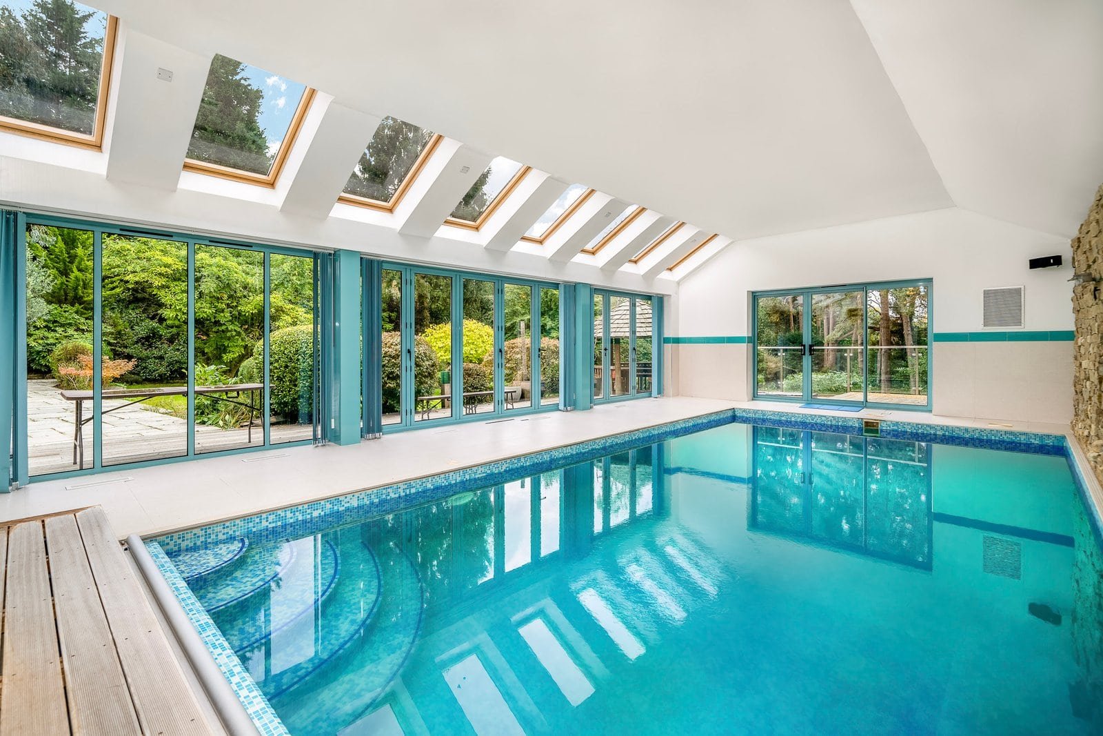 Indoor swimming pool with large glass windows and skylights, modern home leisure area.
