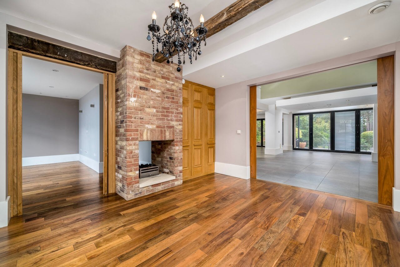 A modern open-plan living area with wooden flooring and large glass doors.