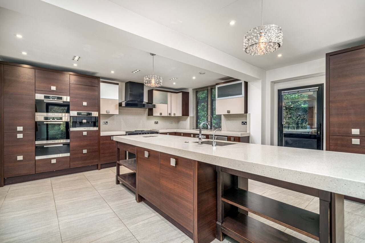 Modern kitchen with dark wood cabinets, white countertops, and stainless steel appliances.