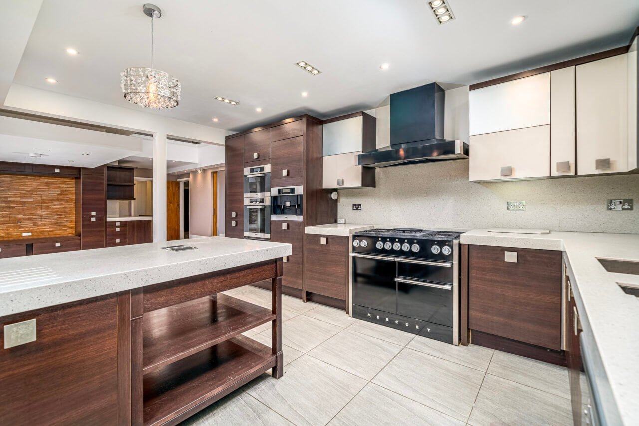 A modern kitchen with dark wood cabinets, stainless steel appliances, and white countertops.