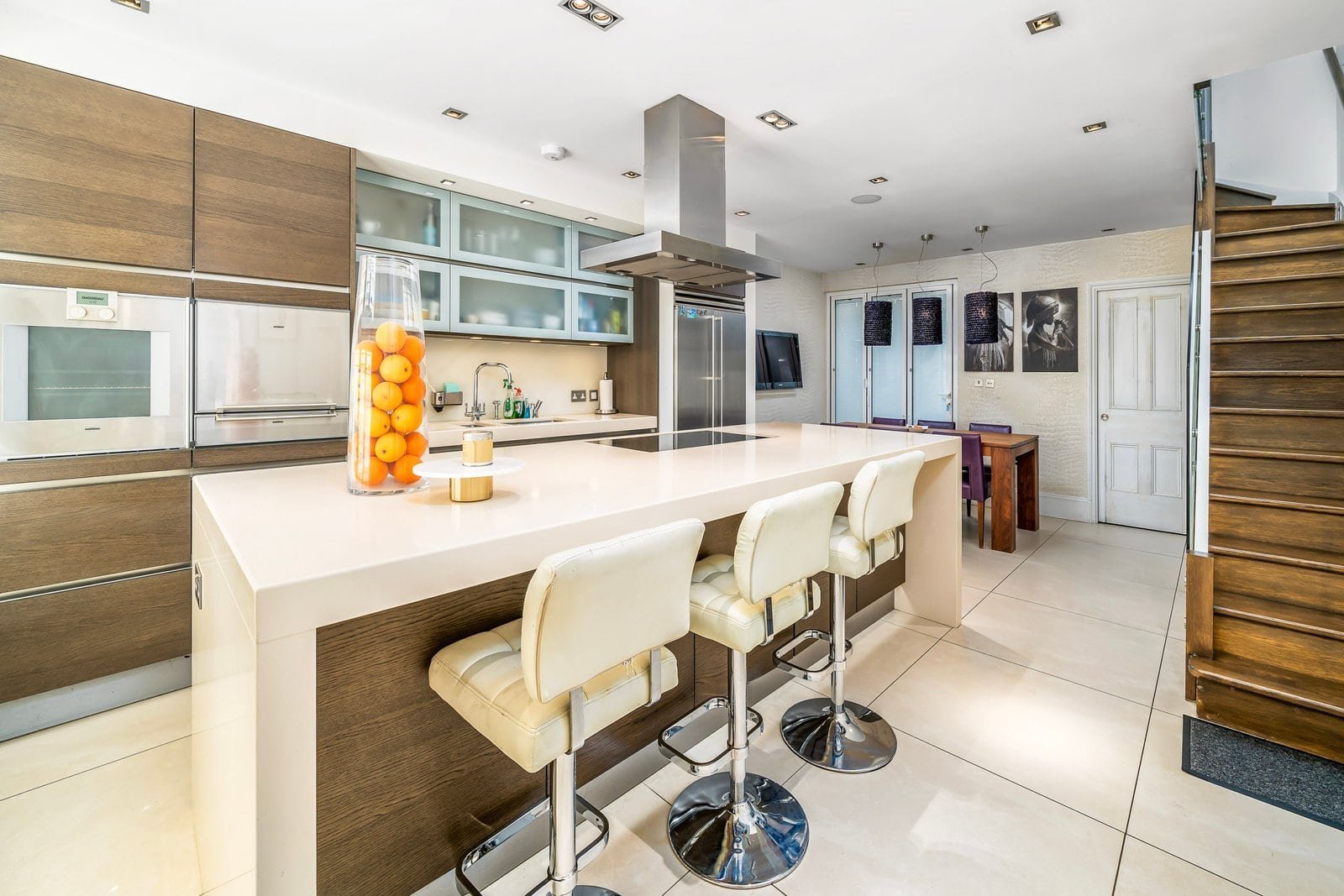 A modern kitchen with white island, wooden cabinets, and bar stools, bright and spacious.