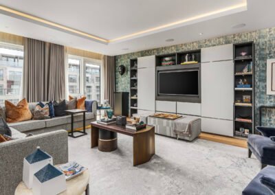 A modern living room with a large TV, stylish furniture, and decorative shelving.