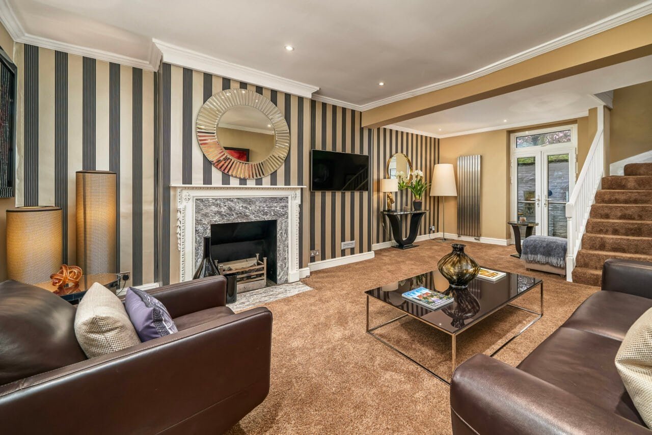 Modern living room with striped wallpaper, fireplace, and comfortable seating.